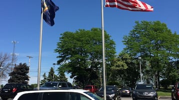 A white minivan parked in a parking lot with a flagpole displaying the American flag and another flag.