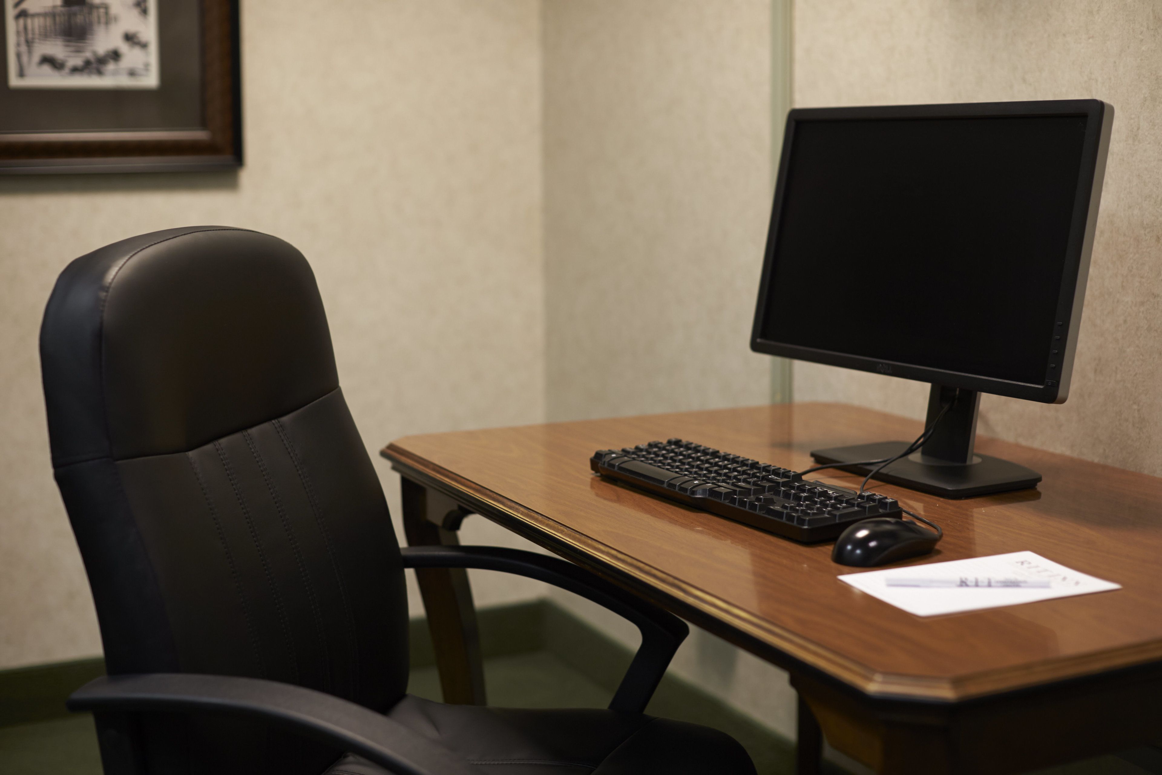 A wooden desk with a computer monitor, keyboard, and mouse.