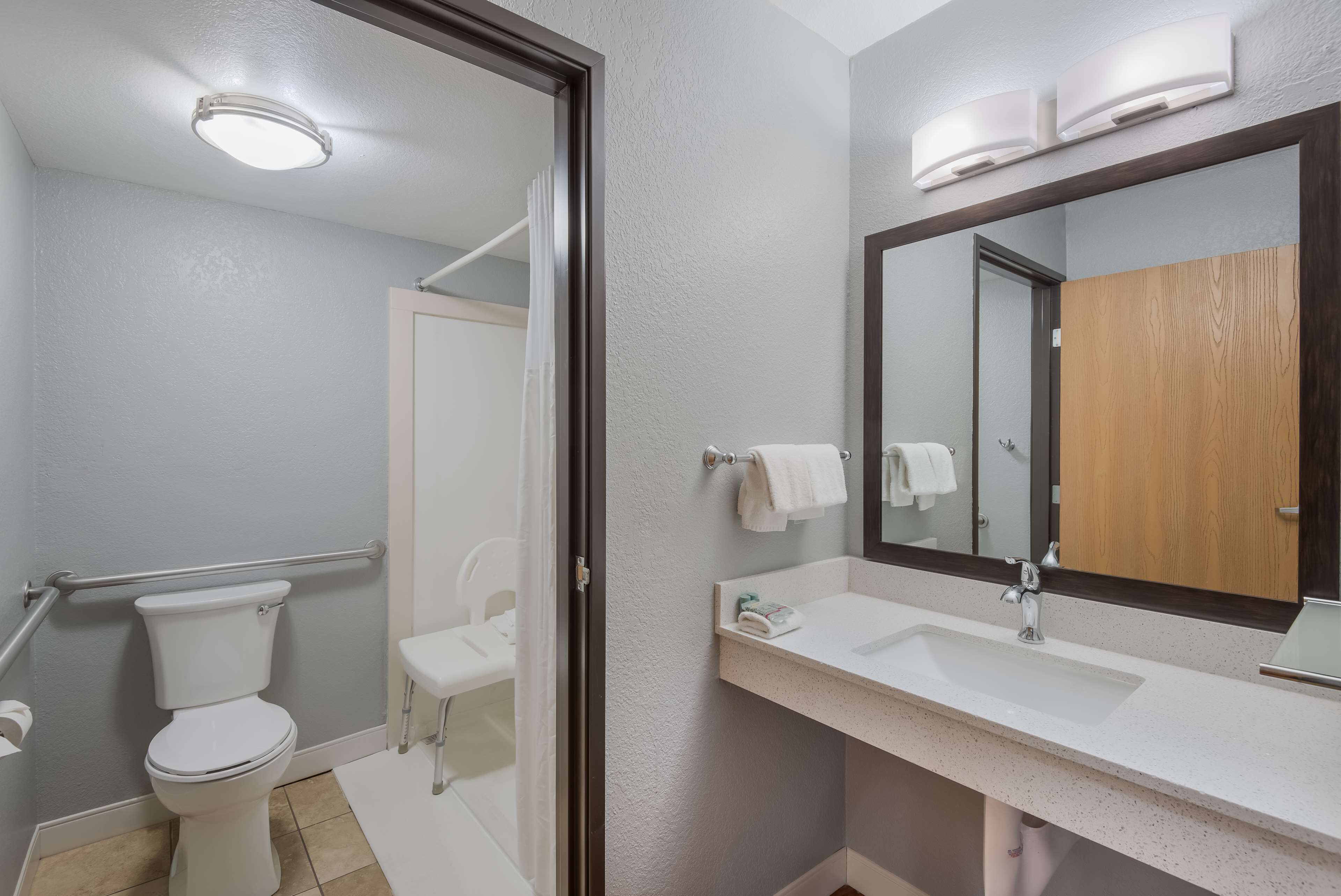 Un baño moderno con inodoro, lavamanos y espejo.