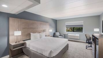 A modern hotel room with a large bed, bedside tables, a desk, and a chair.