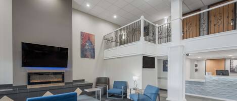 Un hall d’hôtel moderne doté d’un téléviseur à écran plat, d’un espace salon et d’un comptoir d’accueil.