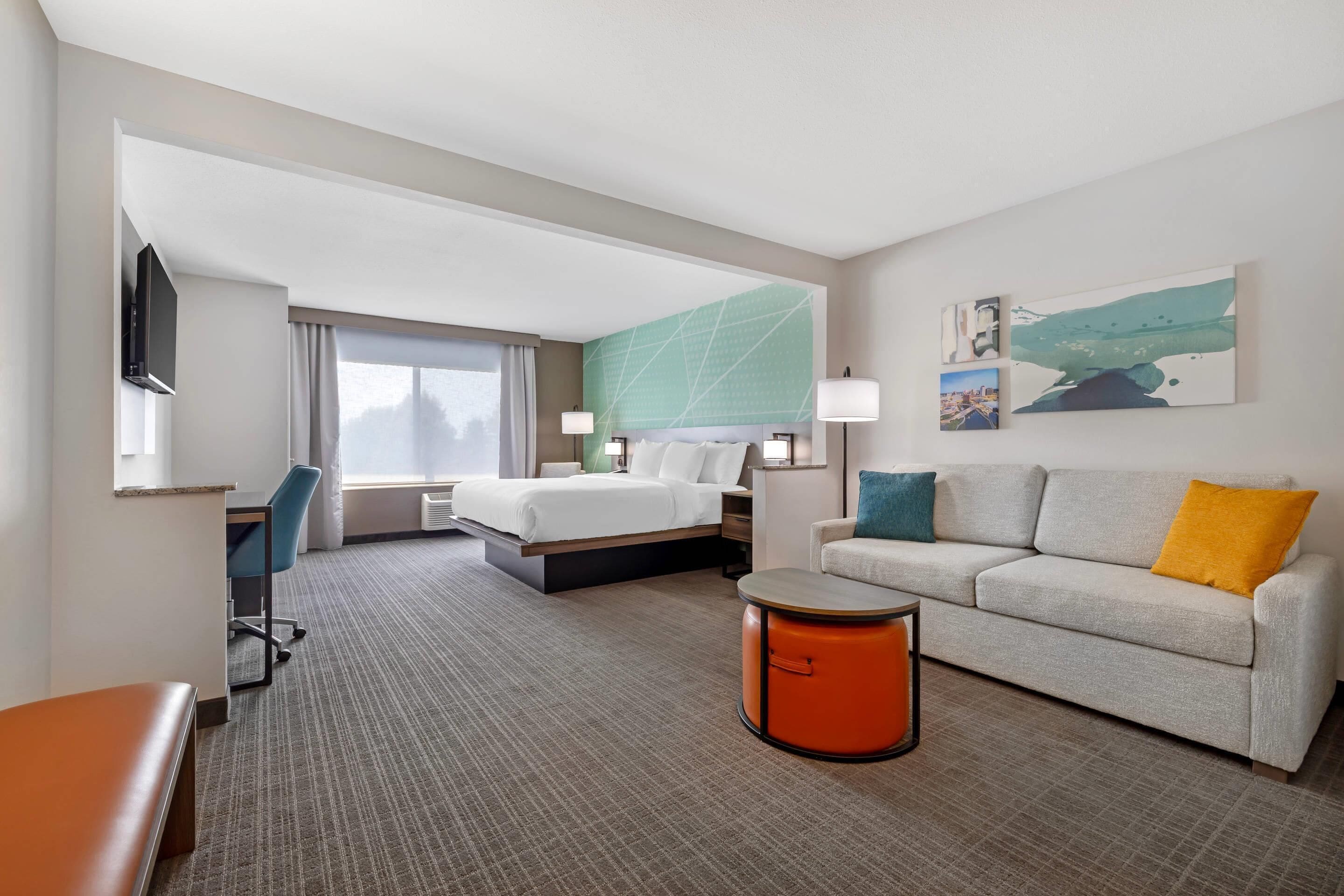 Een hotelkamer met een bed, een sofa, een bureau en een stoel.