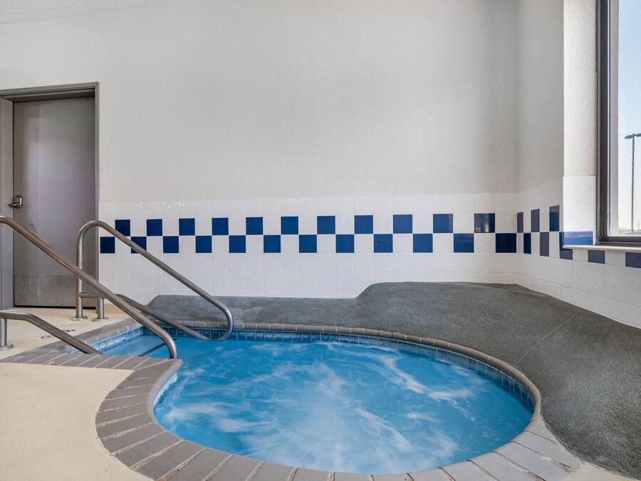 An indoor swimming pool with a checkered tile wall, a door labeled 'Mechanical Room,' and a window with a view outside.