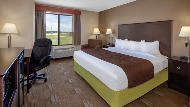 Hotelkamer met een groot bed, een bureau met stoel, een raam met uitzicht op de omgeving, en twee bedlampjes.