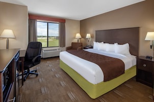 Habitación de hotel con una cama grande, un escritorio con silla, una ventana con vistas al exterior y dos lámparas de noche.