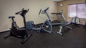 Een fitnessruimte met loopbanden, elliptische trainers en een hometrainer.