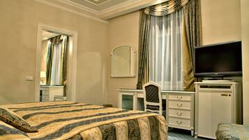 Ein Hotelzimmer mit einem großen Bett, einem Schreibtisch mit Stuhl, einem Fernseher und einem Kleiderschrank.