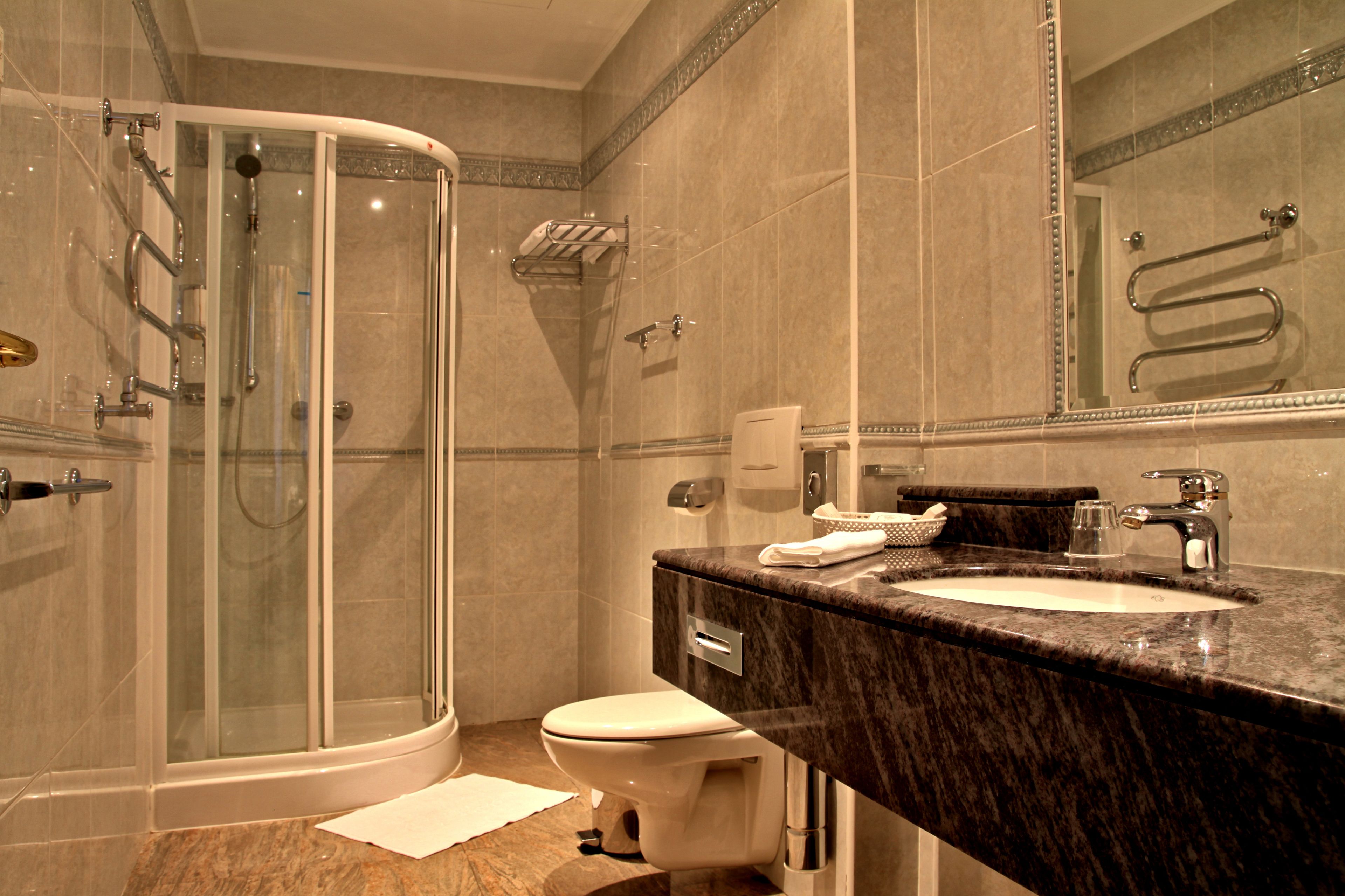 A modern bathroom with a glass-enclosed shower, a marble sink, and a toilet.