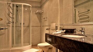 A modern bathroom with a glass-enclosed shower, a marble sink, and a toilet.