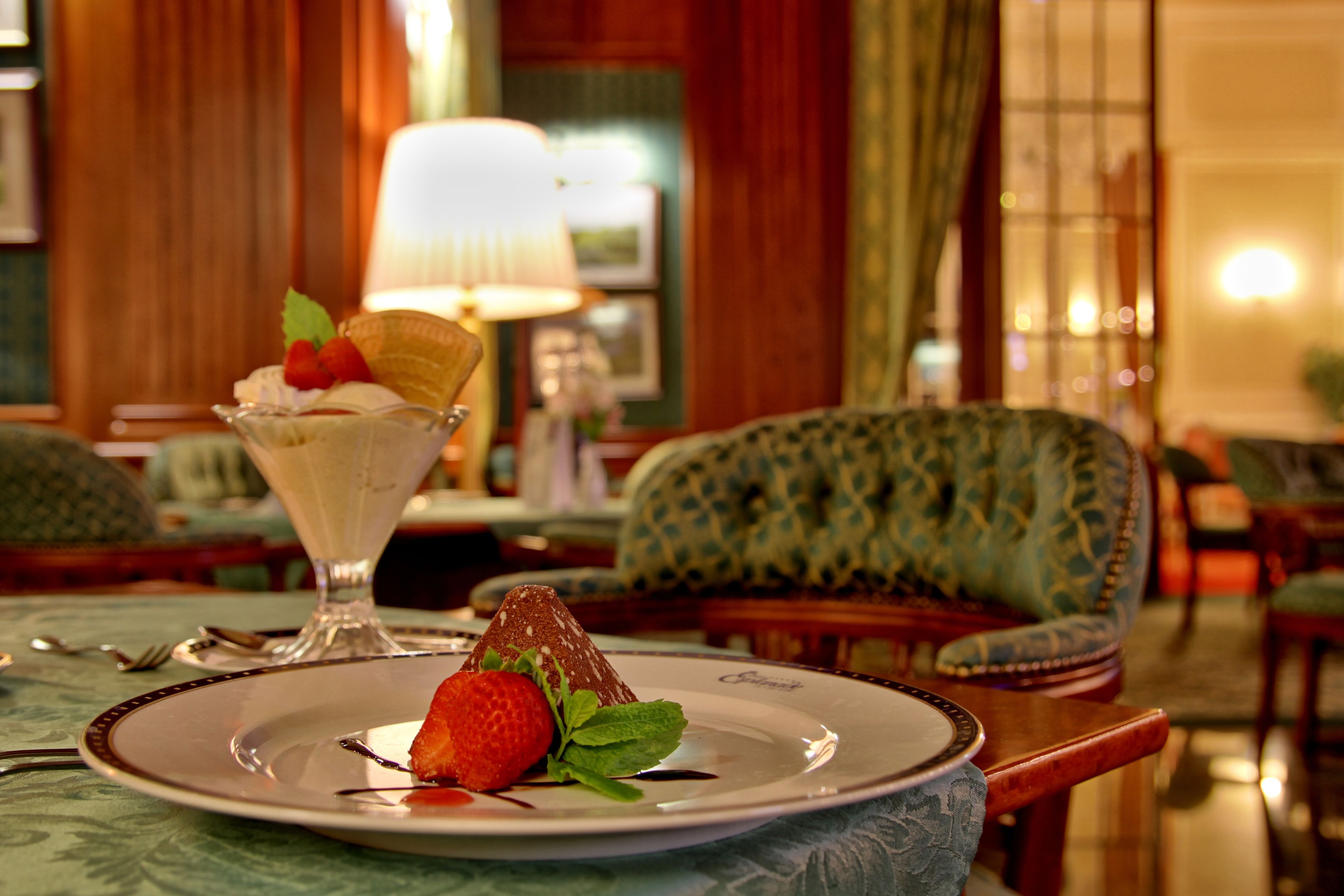 Un dessert présenté sur une assiette, agrémenté de fraises et de menthe, une lampe et une chaise à motifs dans un coin repas.