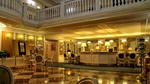 A grand hotel lobby with a checkered floor, a reception desk, and a balcony with a balustrade. - Esplanade Spa and Golf Resort (Marianske Lazne)