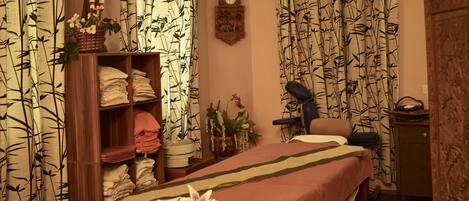 Una habitación con una cama, una camilla de masaje, un armario de madera y un reloj de pared.