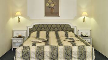 A bed with a patterned bedspread, two bedside tables with lamps, and a framed picture on the wall.