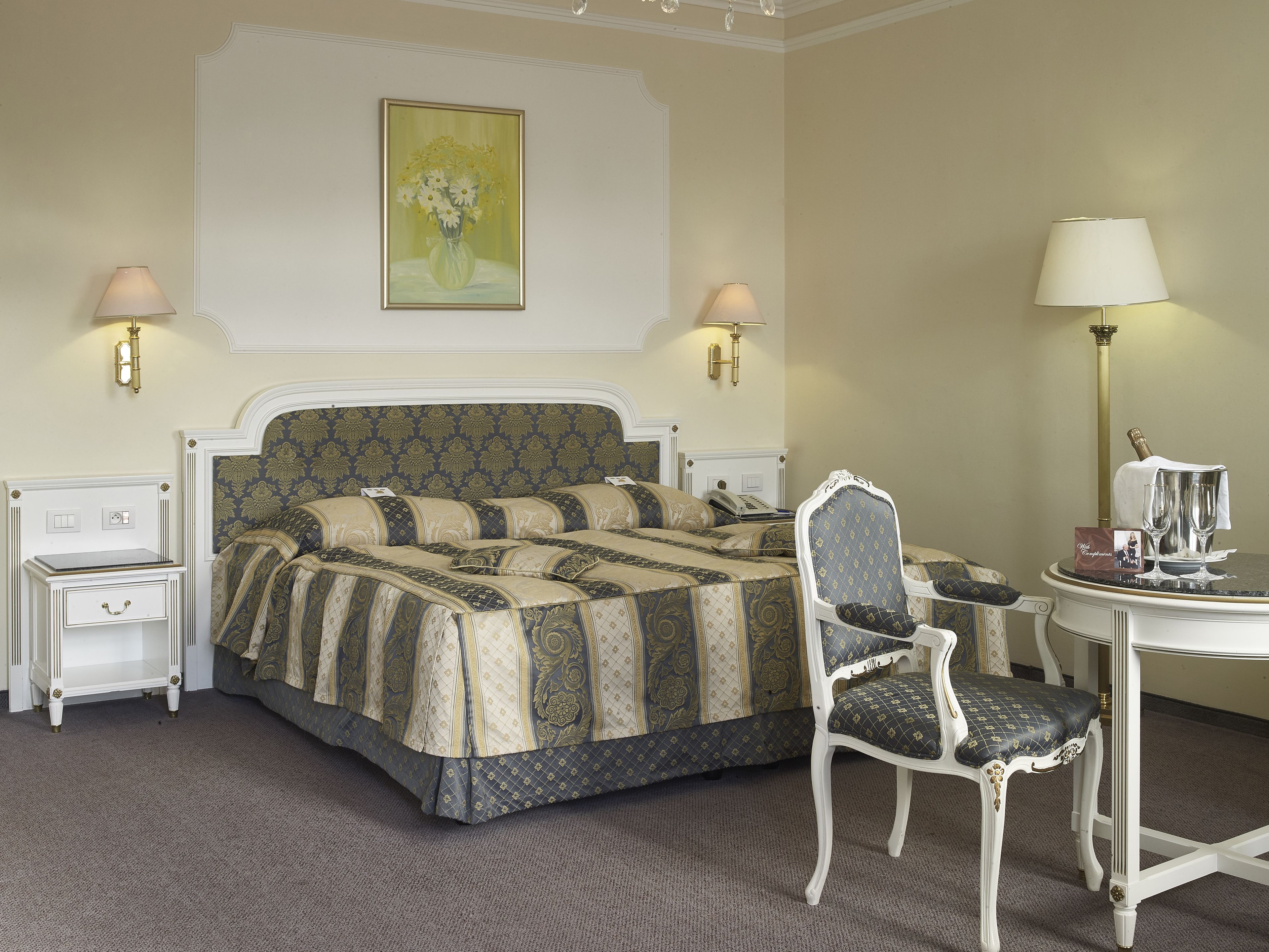Ein Hotelzimmer mit einem großen Bett, zwei Nachttischen, einem Sessel, einem Schreibtisch und einer Lampe.