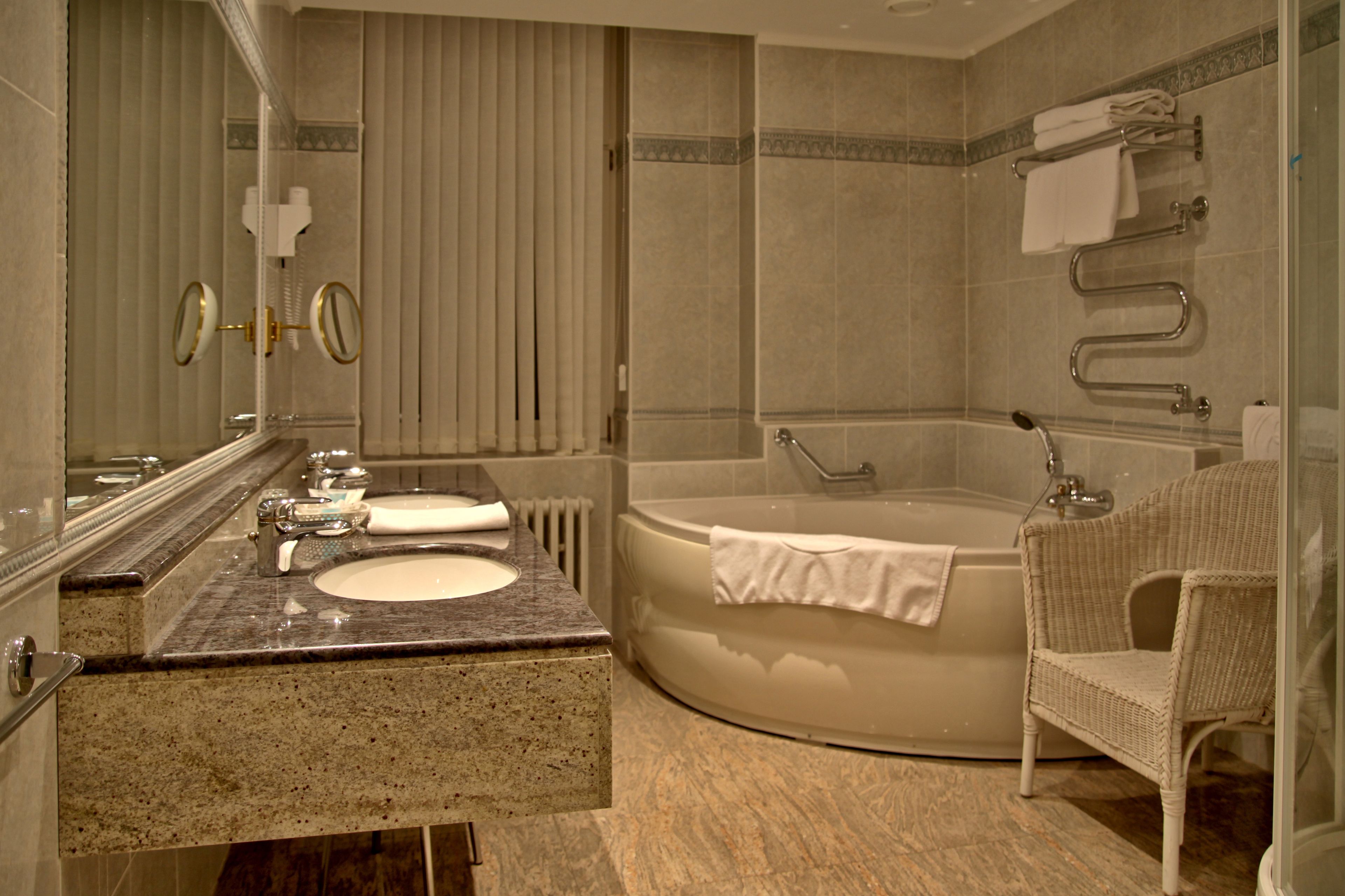 A modern bathroom with a freestanding bathtub, a sink with a vanity, a mirror, and a wicker chair.