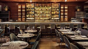 A bar area with multiple seating options, including round tables and booths, and a well-stocked bar with various bottles and glasses. - W New York - Times Square (New York)