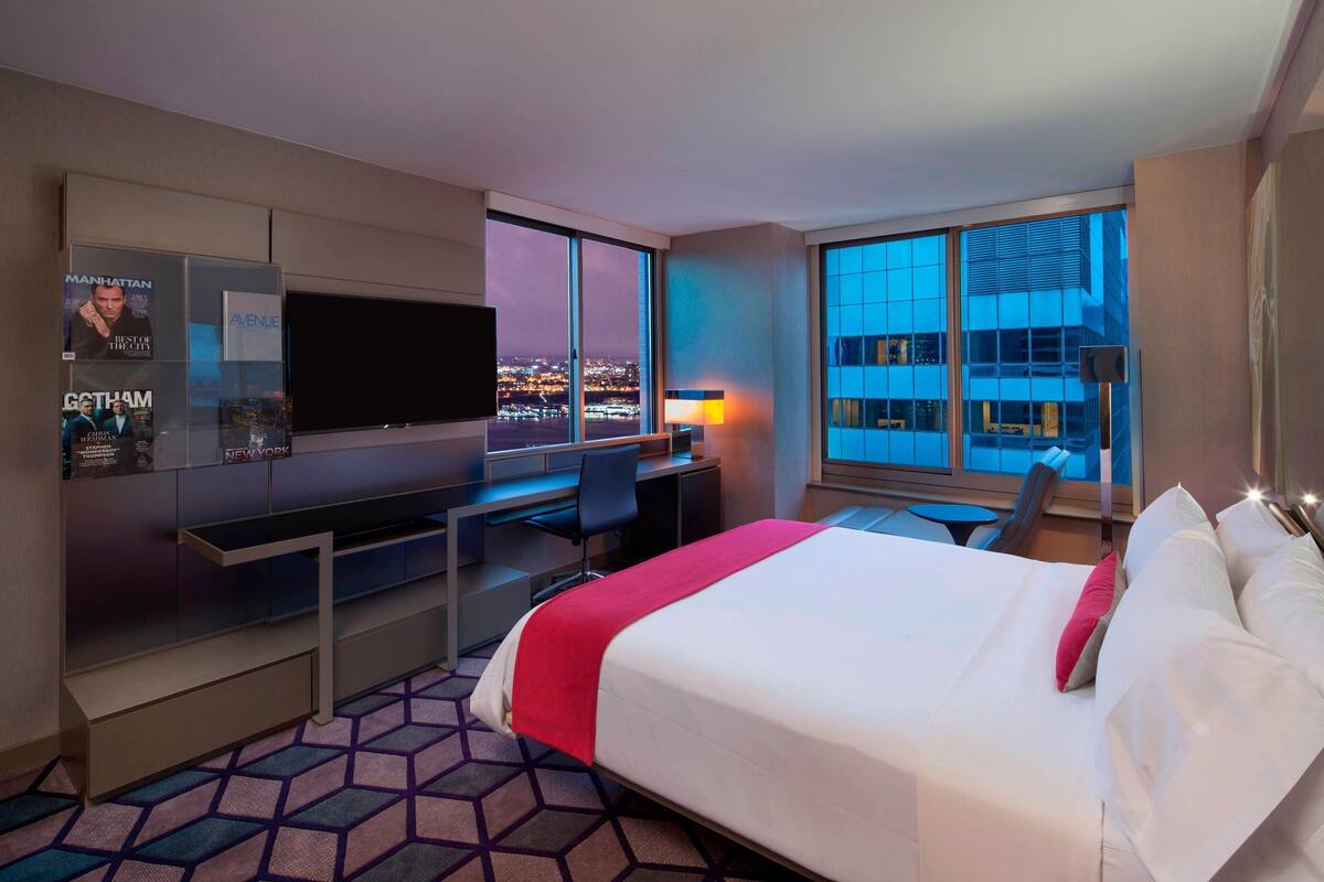 Una habitación de hotel con cama, escritorio y televisor.