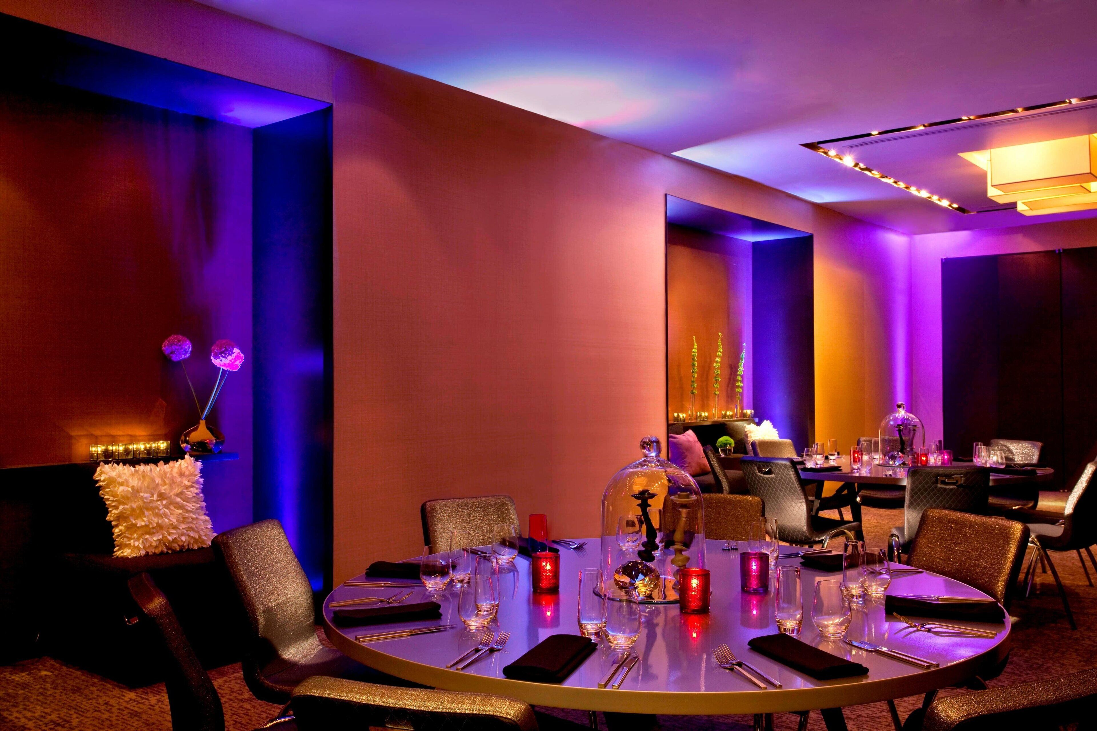 A dining area with a round table set for four, surrounded by chairs.
