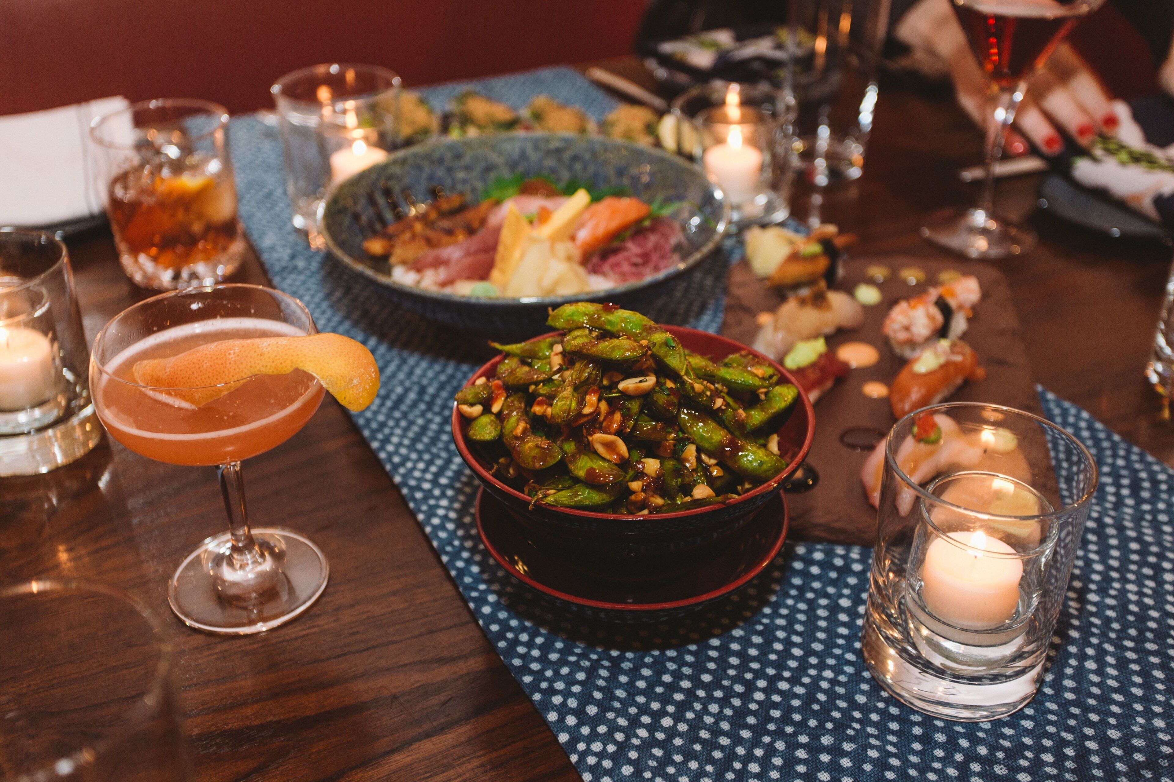 A dining table with a variety of dishes, drinks, and candles.