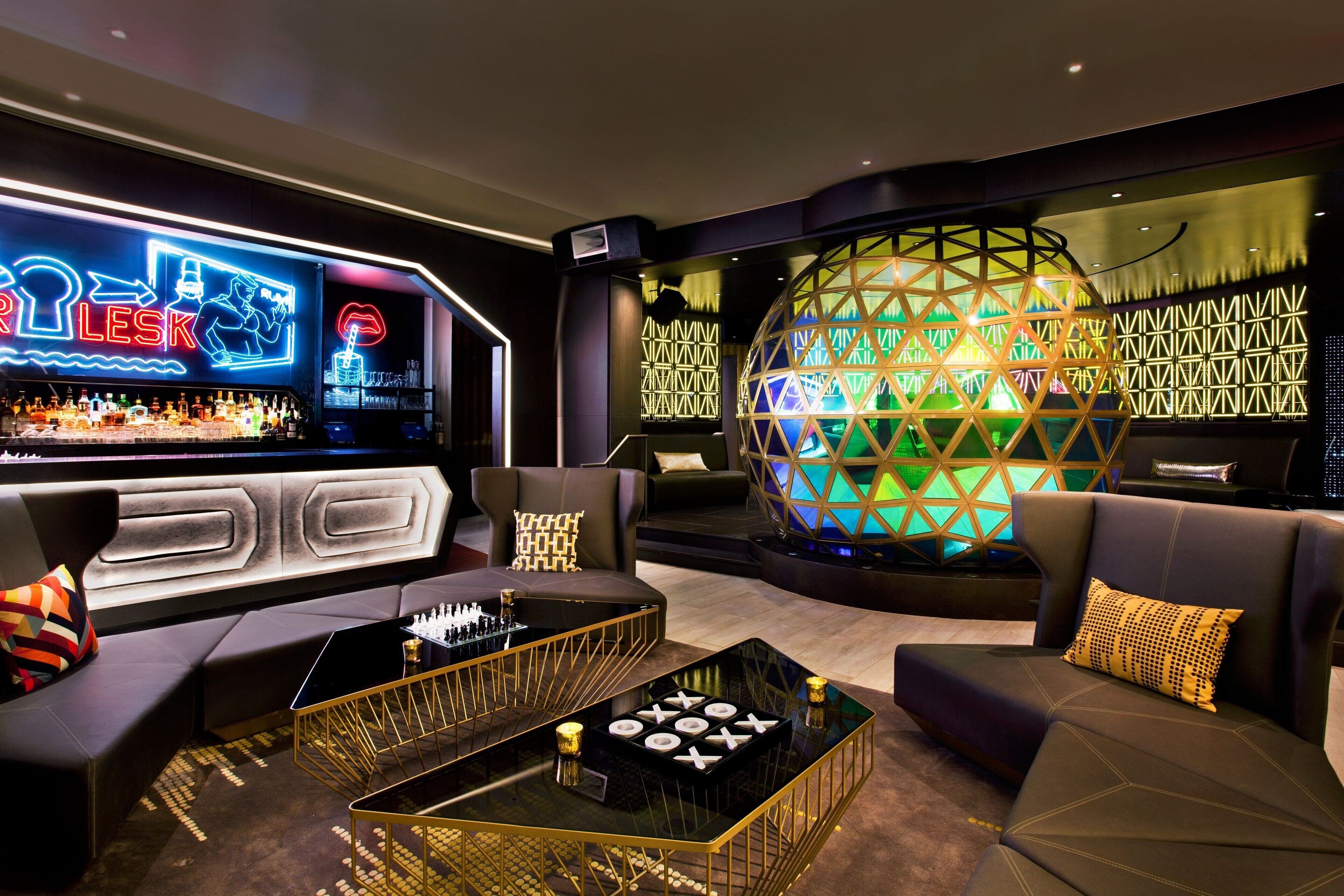 Een moderne bar met een neonbord, een grote bolvormige lamp en een schaakbord op een glazen salontafel.