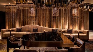A modern lounge area with a curved seating arrangement, a central coffee table, and a decorative backdrop with vertical elements. - W New York - Times Square (New York)