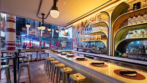 A bar area with stools, a counter with bottles, and a mural on the wall. - W New York - Times Square (New York)