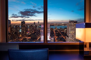 A bar area with stools, a counter with bottles, and a mural on the wall. at W New York - Times Square