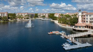 A waterfront hotel with a fountain, dock, and multiple boats.