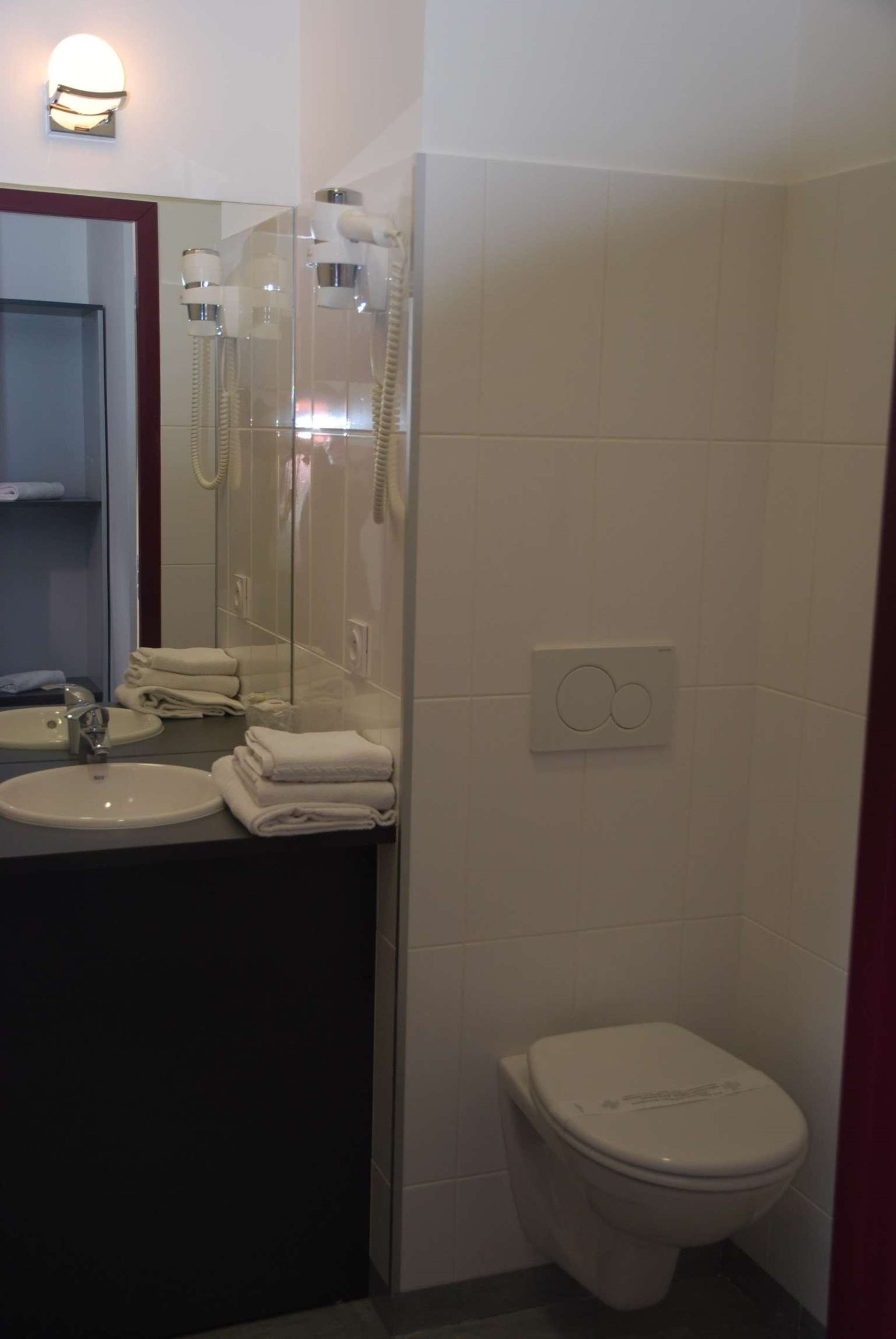 Un baño con lavamanos, espejo e inodoro.