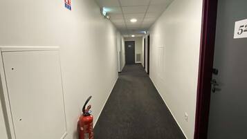 A hallway with a fire extinguisher, a fire alarm, and a door with the number 52.