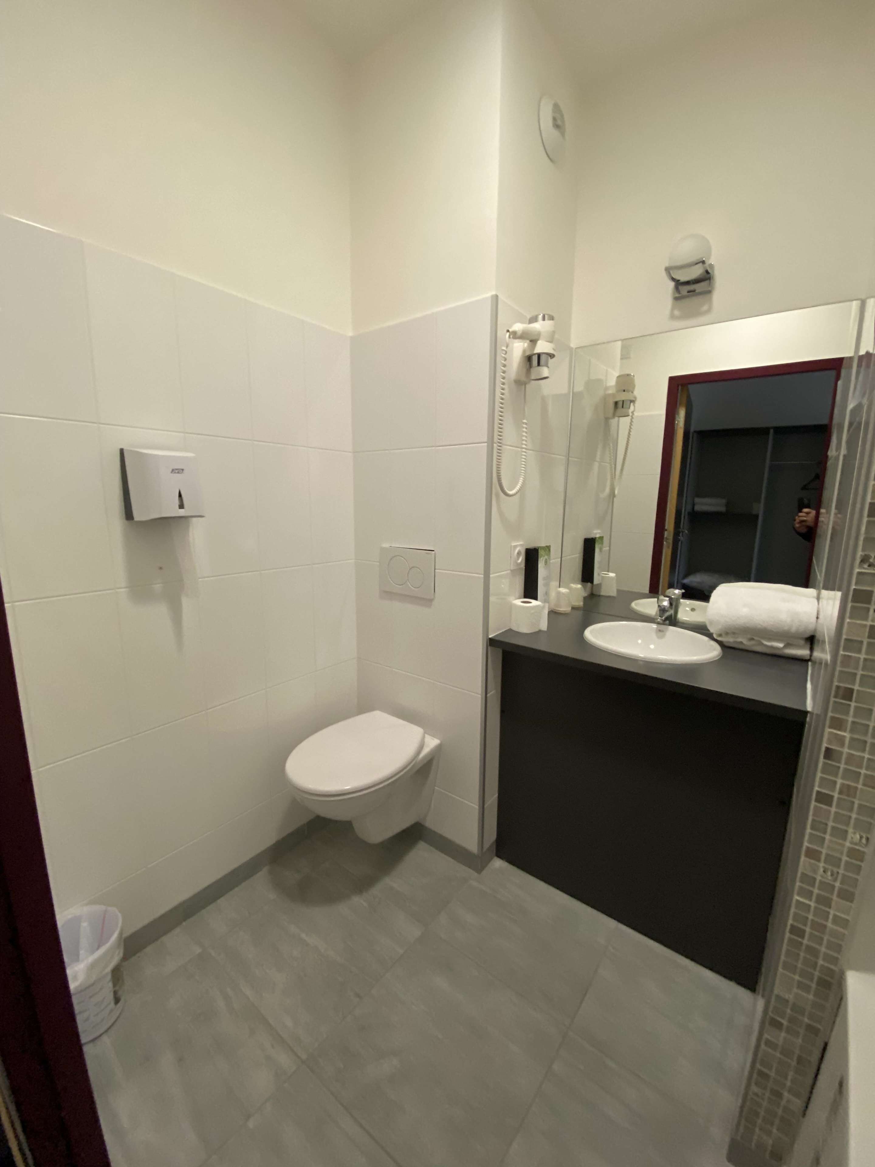 Et lille badeværelse med toilet, vask og bruser.