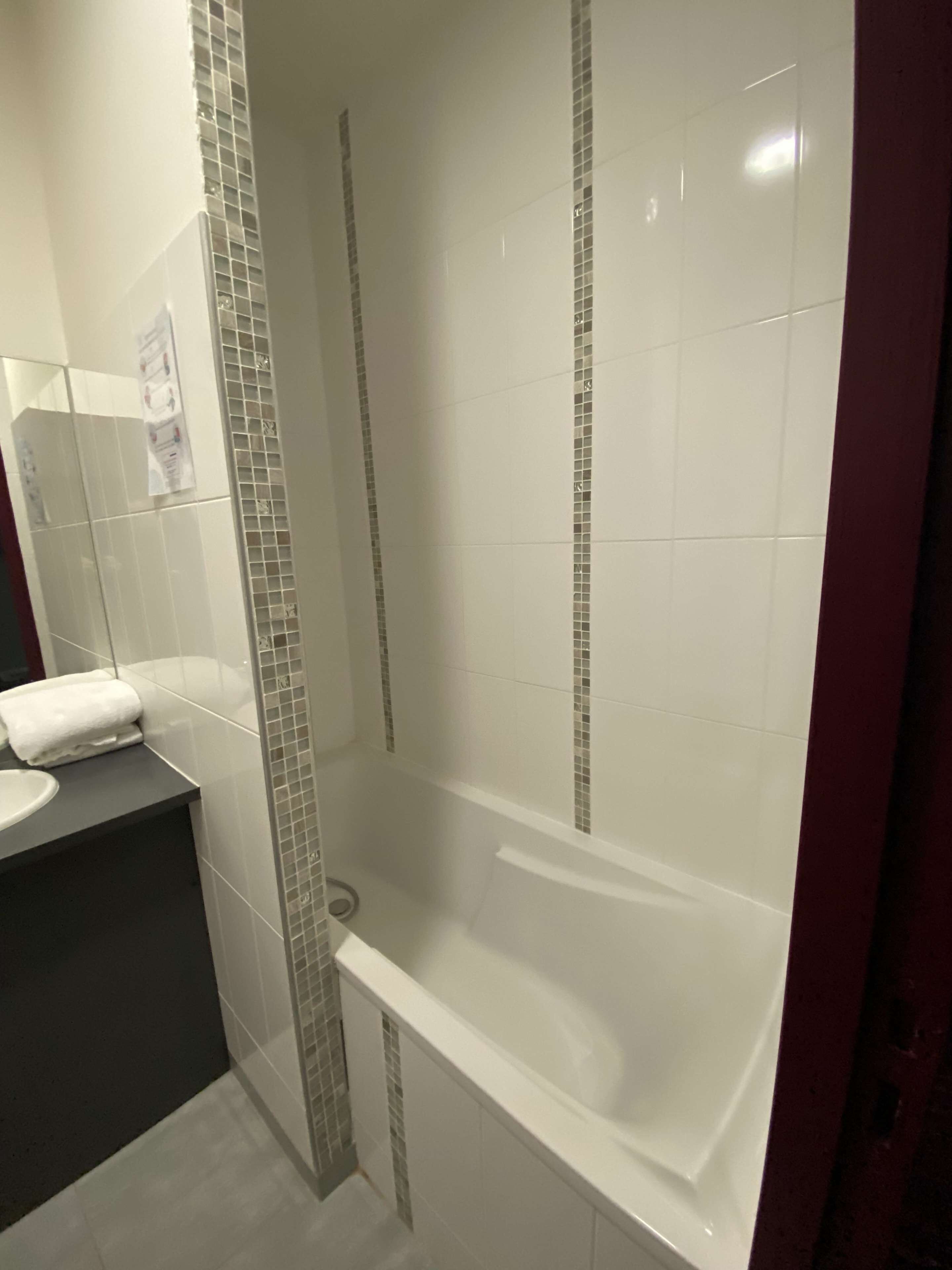 A bathroom with a bathtub, a sink, and a tiled shower area.