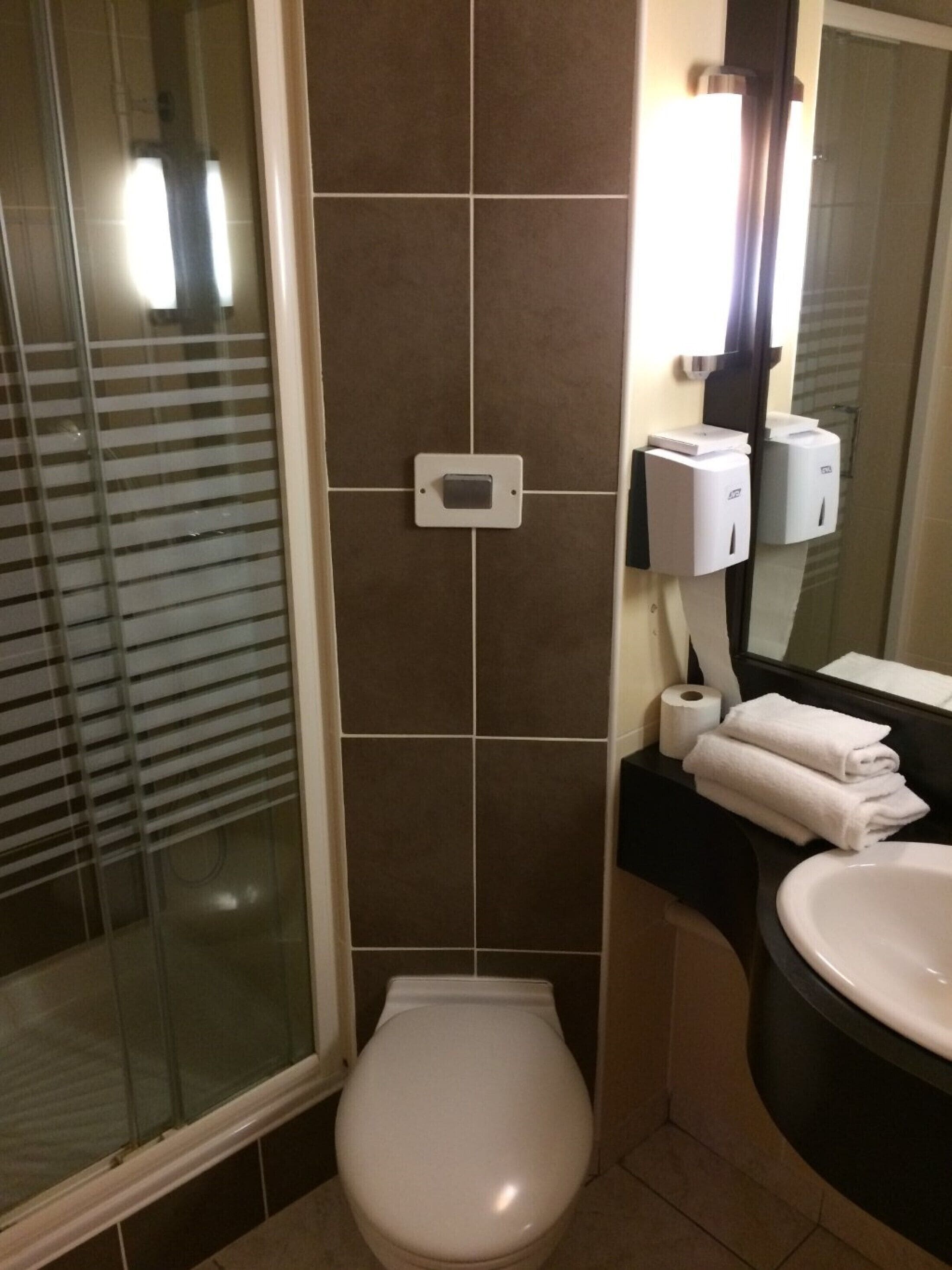 A bathroom with a toilet, a sink, and a hand dryer.