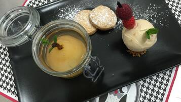 Une assiette à dessert avec un pot de sauce, des biscuits et un dessert garni d’une baie et de menthe.