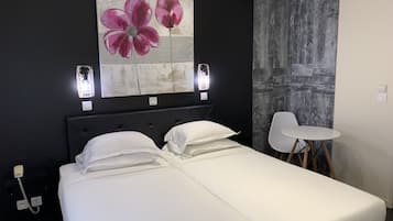 Una habitación de hotel con una cama, una silla blanca y un cuadro de flores en la pared.