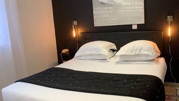 Ein modernes Schlafzimmer mit einem schwarzen Kopfteil, einer gesteppten schwarz-weißen Bettdecke und einem gemusterten Boden.