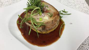 Un plat garni d’herbes vertes et d’oignons, servi dans une assiette blanche accompagnée d’une sauce brune.