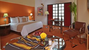 A hotel room with a bed, a dining table, a chair, a vase with flowers, and a lamp. - Hotel Misión Monterrey Centro Histórico (Monterrey)