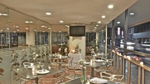 A restaurant with outdoor seating, tables set with candles, and a view of the street. - Hotel Misión Monterrey Centro Histórico (Monterrey)