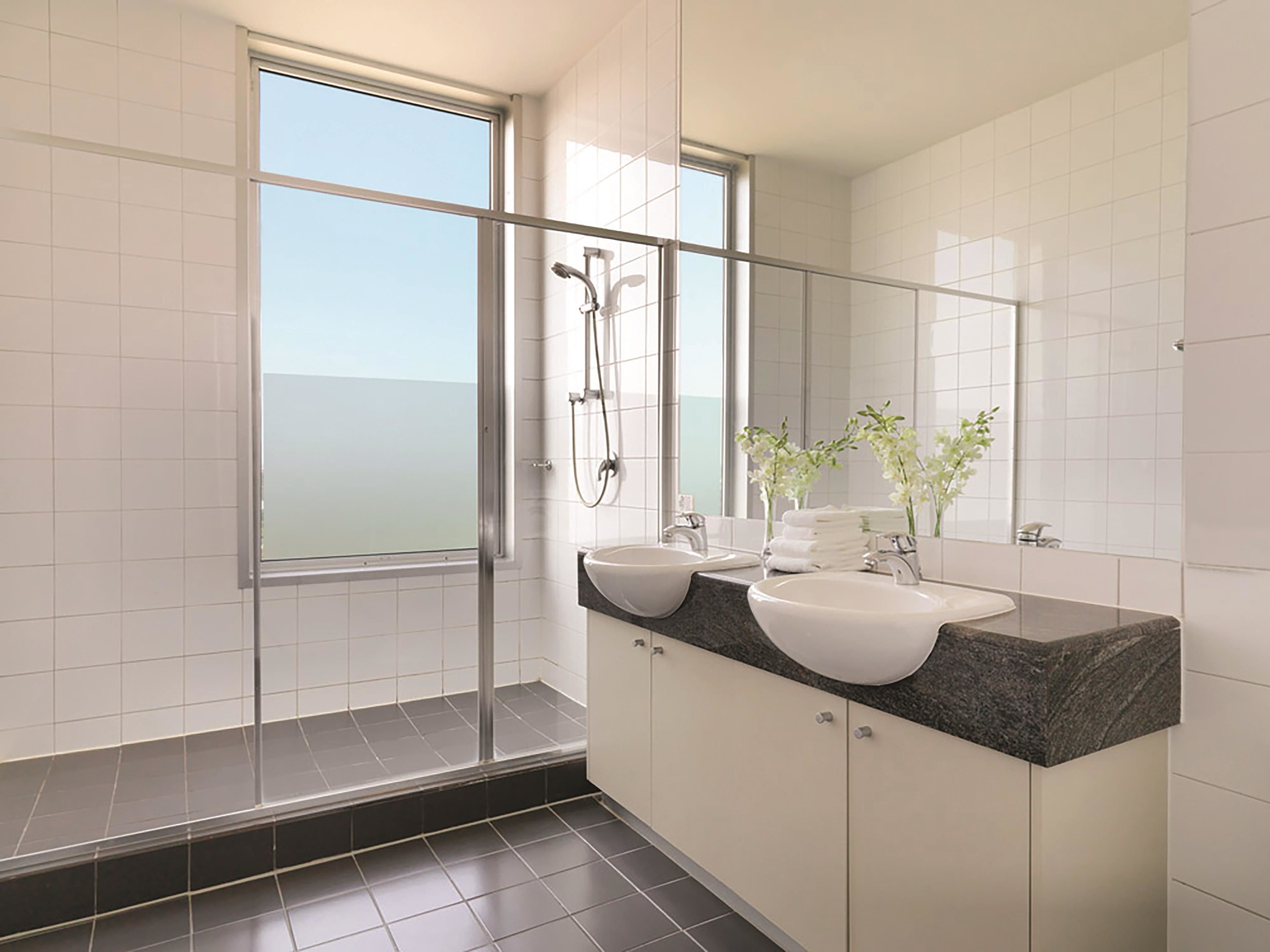 Ein modernes Badezimmer mit zwei Waschbecken, einer Dusche und einem großen Fenster mit Blick.