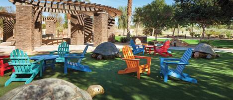 Un patio con pérgola de madera, mobiliario exterior y esculturas de tortugas artificiales.