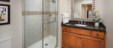 A modern bathroom with a glass-enclosed shower, a sink with a wooden vanity, and a large mirror with a decorative frame.