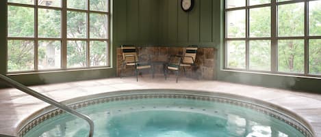 A pool area with a stone wall, two chairs, and a clock on the wall.