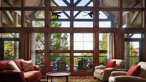 Una habitación amplia con ventanas grandes, vigas de madera y dos ventiladores de techo.