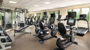 A gym with multiple cardio machines, weight machines, and dumbbells.