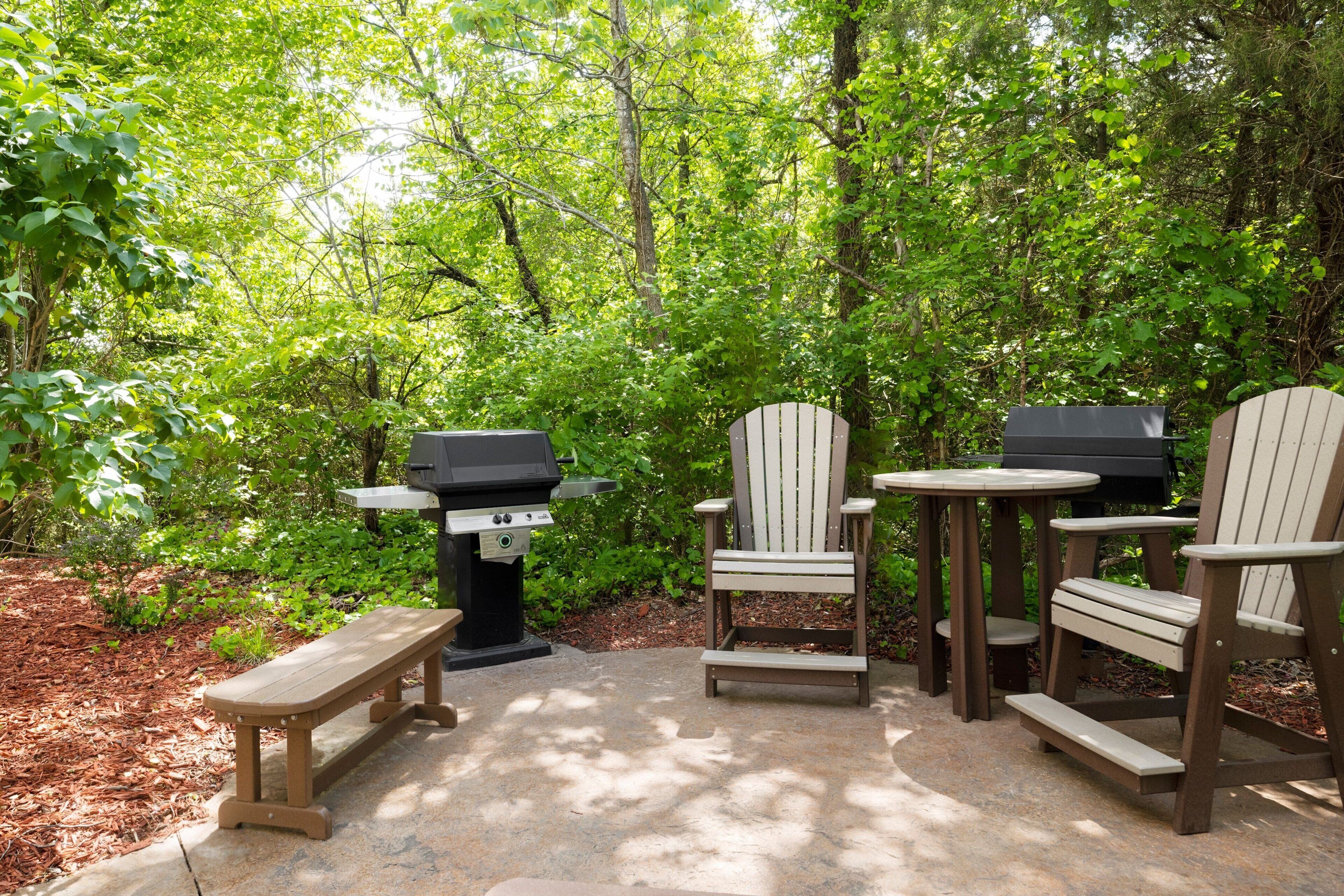 An outdoor patio with a grill, wooden chairs, and a bench.