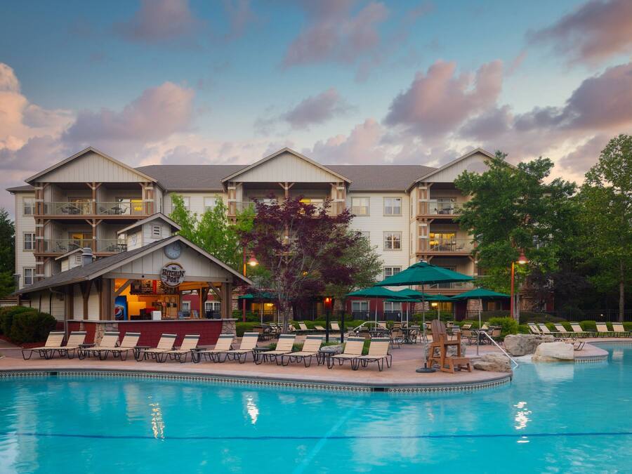 A hotel with a pool area, lounge chairs, and a bar.