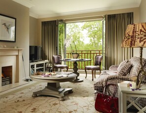 Una sala de estar acogedora con chimenea, televisión, mesa de comedor con sillas y sofá con un cojín estampado.