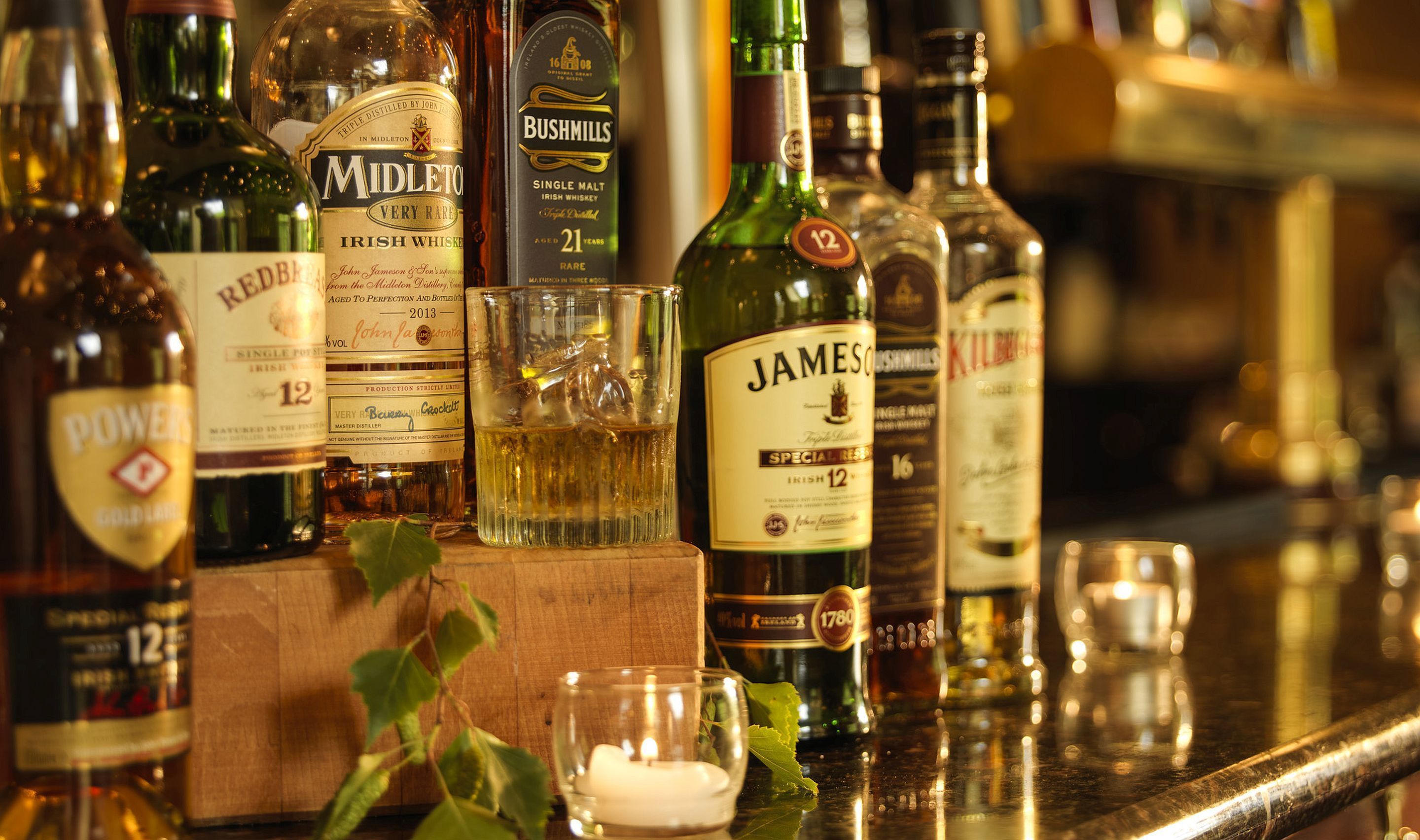 A variety of whiskey bottles on a bar counter.
