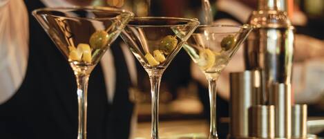 A bartender pouring a drink into a martini glass.